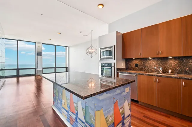 a kitchen with stainless steel appliances granite countertop a stove a sink and a refrigerator with wooden floor