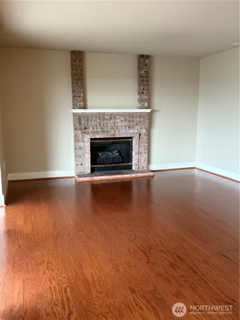 a view of empty room with wooden floor and fireplace