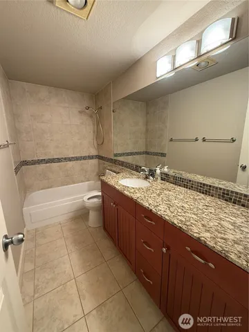 a bathroom with a granite countertop sink a toilet and bathtub