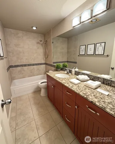 a bathroom with a granite countertop sink a toilet a mirror and bathtub
