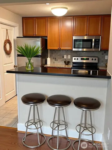 a kitchen with stainless steel appliances a table chairs refrigerator and microwave