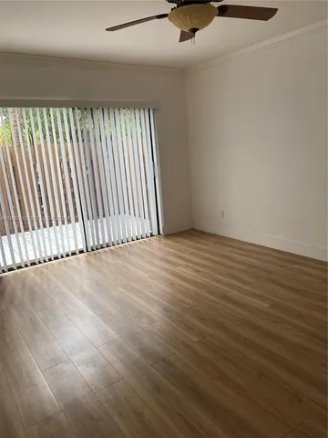 an empty room with wooden floor chandelier fan and windows