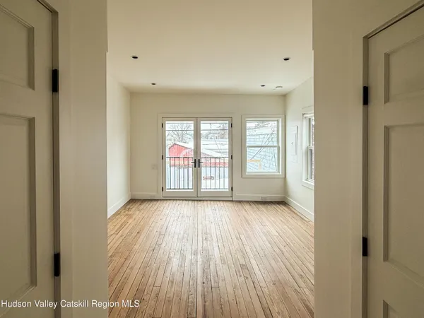 a view of an empty room with wooden floor and a window