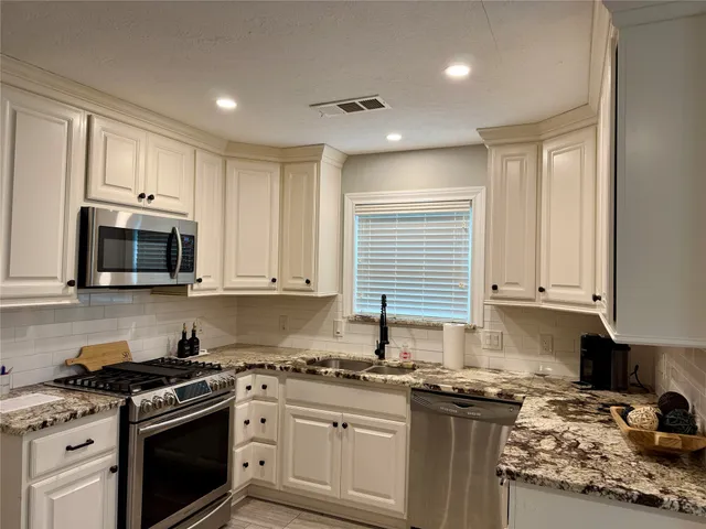 a kitchen with stainless steel appliances granite countertop a stove a sink and a microwave