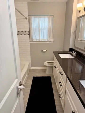 a bathroom with a granite countertop sink toilet a large mirror a vanity and a shower
