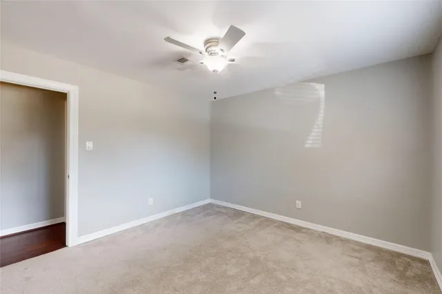 an empty room with a ceiling fan and a window