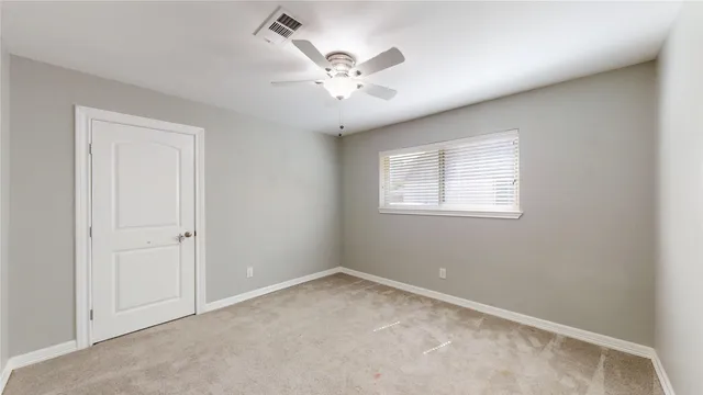 an empty room with a ceiling fan and a window