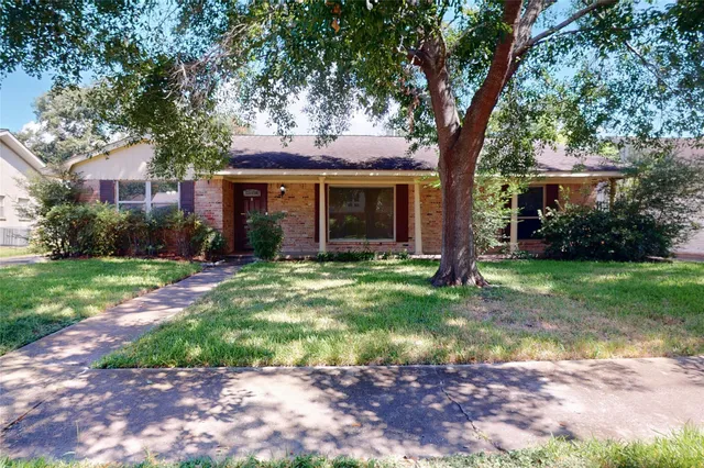 a view of a house with a yard tree and a large tree