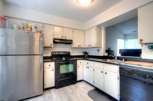 a kitchen with stainless steel appliances granite countertop a refrigerator a stove a sink and a granite counter tops with wooden floors