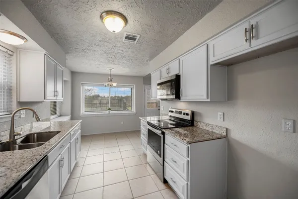 a kitchen with granite countertop a sink stainless steel appliances and cabinets
