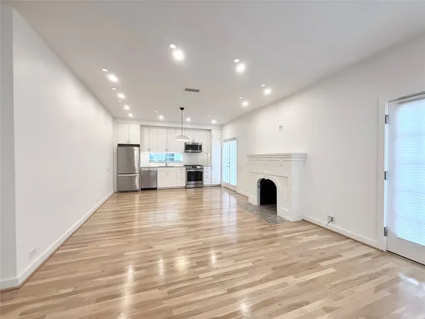 a view of empty room with wooden floor and fireplace