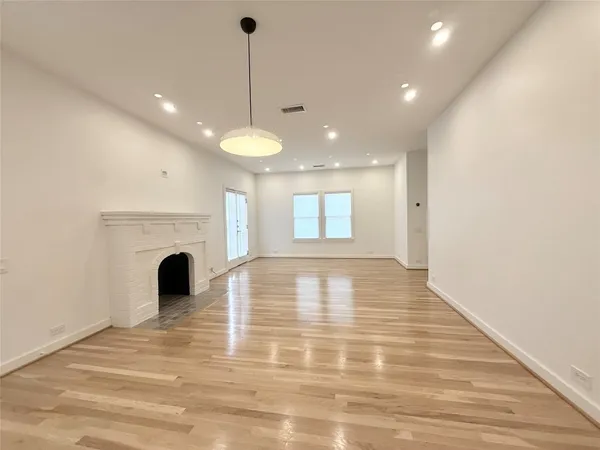 a view of empty room with wooden floor and fireplace