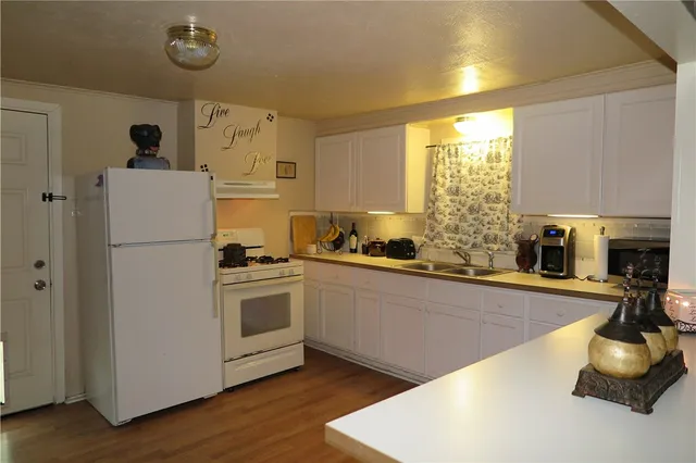 a kitchen with stainless steel appliances granite countertop a refrigerator a sink a stove and a refrigerator