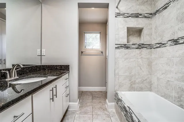 a bathroom with a granite countertop sink a mirror and a bathtub