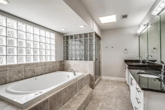 a bathroom with a tub a sink a mirror and a window