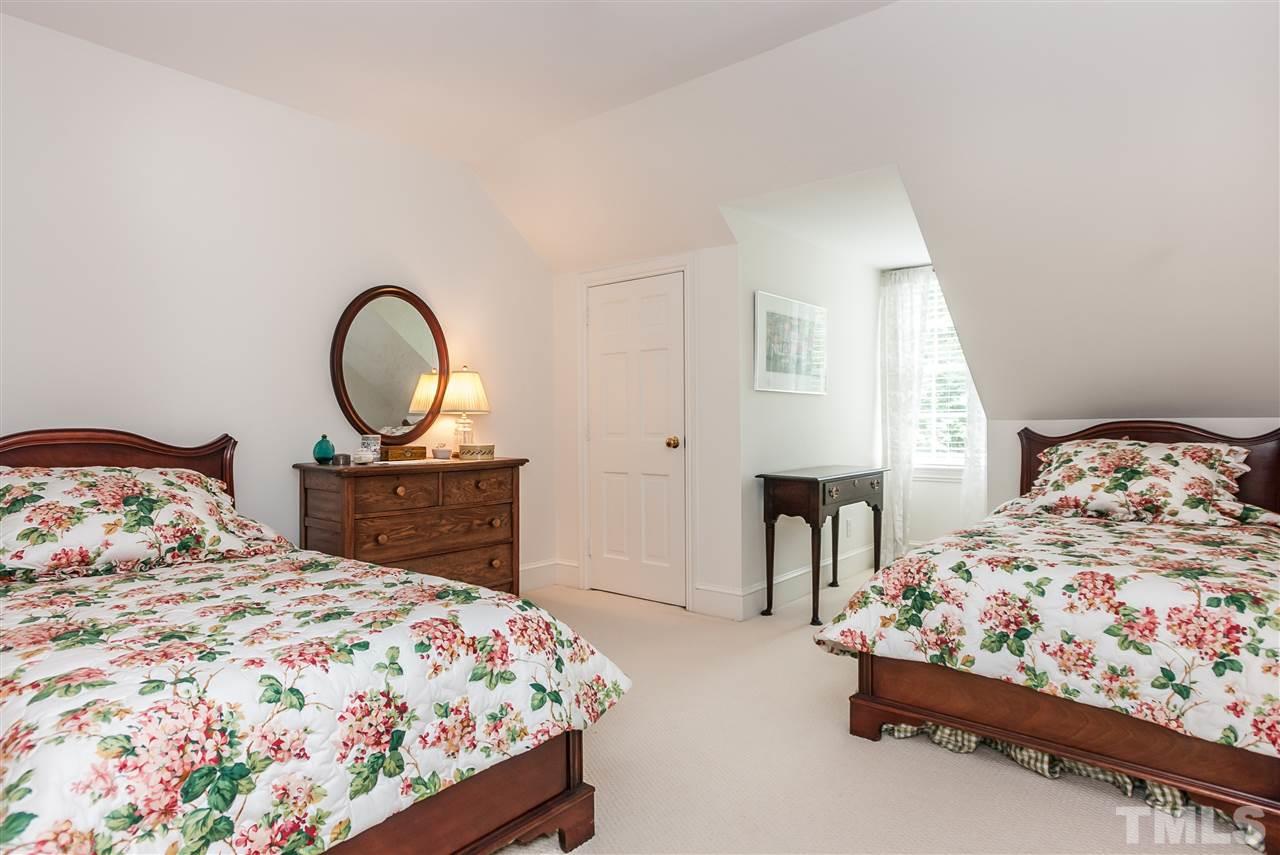 3313 Landor Road Raleigh, NC 27609 - Photo 21 of 25 a bedroom with a bed mirror on dresser and a chandelier