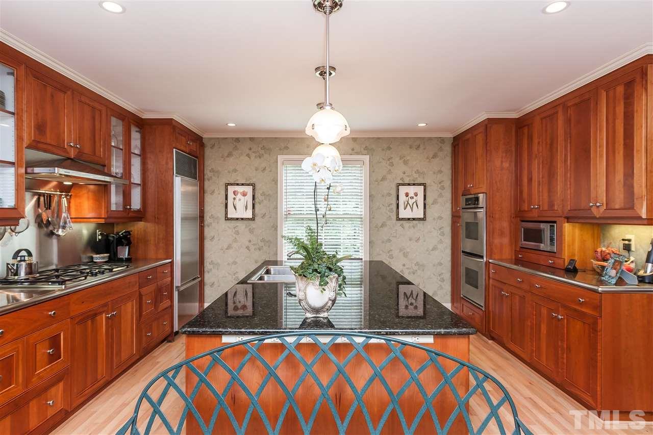 3313 Landor Road Raleigh, NC 27609 - Photo 8 of 25 a dining room with wooden floor a chandelier a wooden table and chairs