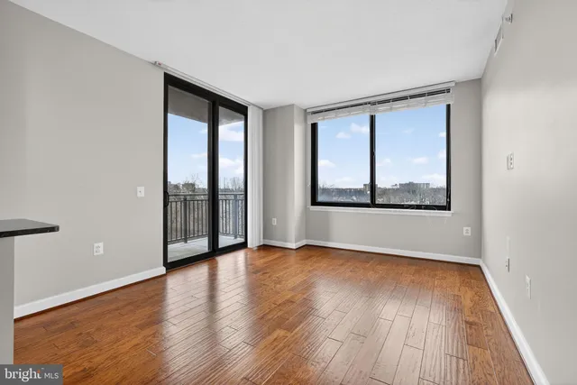 a view of an empty room with wooden floor and a window
