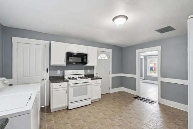 a view of a kitchen with sink electronic appliances and cabinets