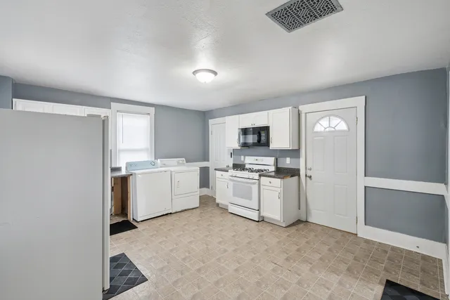 a kitchen with white cabinets and white appliances