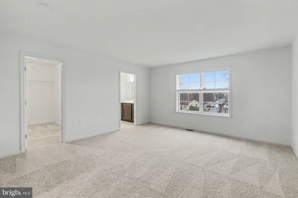 an empty room with windows and refrigerator