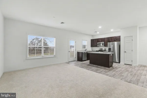 a view of kitchen with stainless steel appliances granite countertop a stove top oven a sink a refrigerator and white cabinets