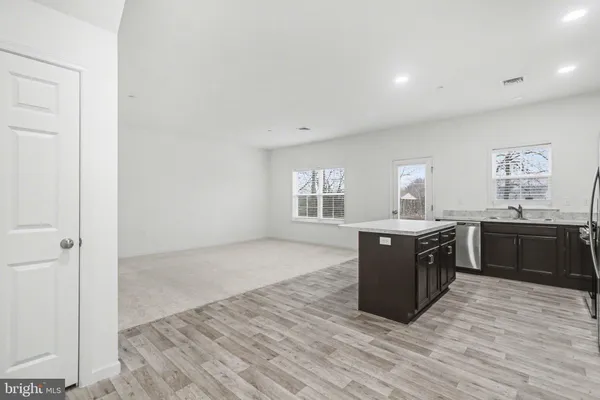 a large room with kitchen island wooden floors and stainless steel appliances