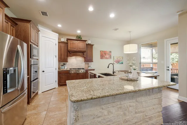 a large kitchen with kitchen island a large counter top stainless steel appliances and cabinets