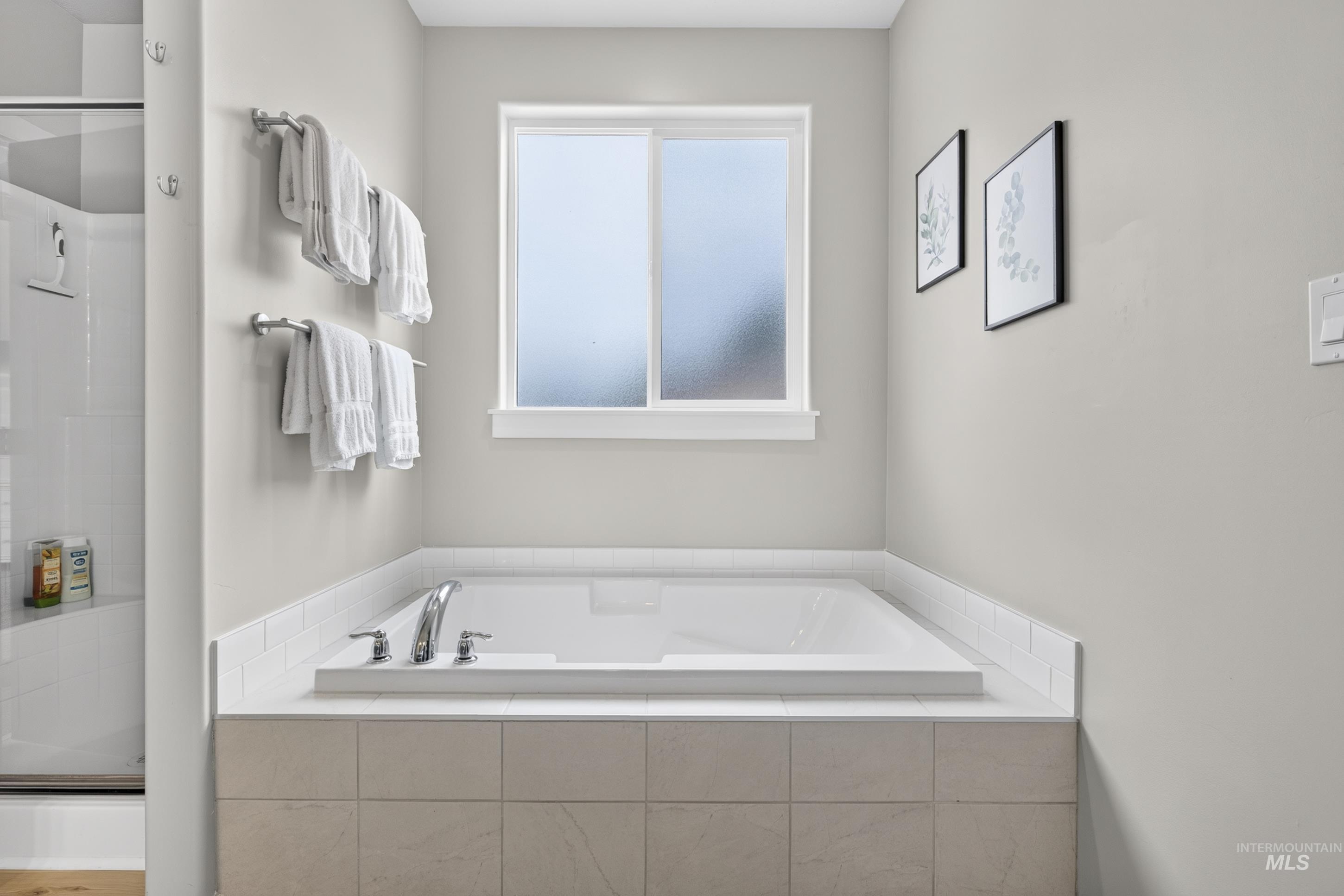 132 Mores Creek Rim Road Boise, ID 83716 - Photo 22 of 44 Built-in soaking tub with chrome fixtures, surrounded by light-toned tile, and a frosted window