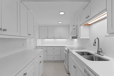a kitchen with white cabinets sink and dishwasher