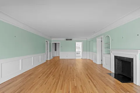 a view of empty room with wooden floor and fireplace