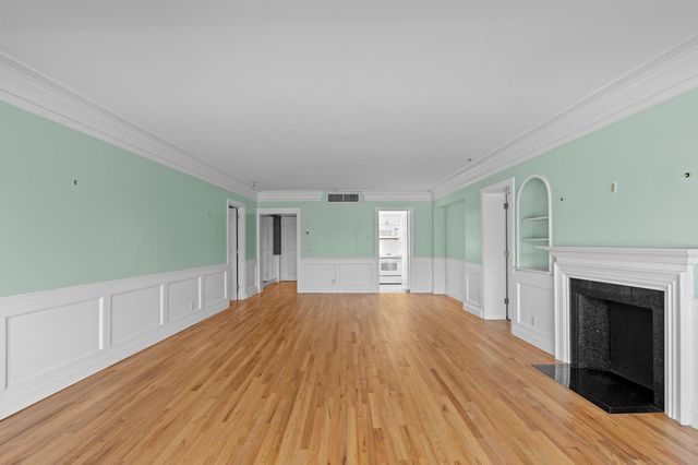 a view of empty room with wooden floor and fireplace