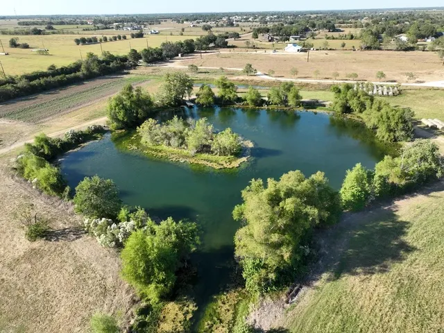 an aerial view of water body with boats and trees all around