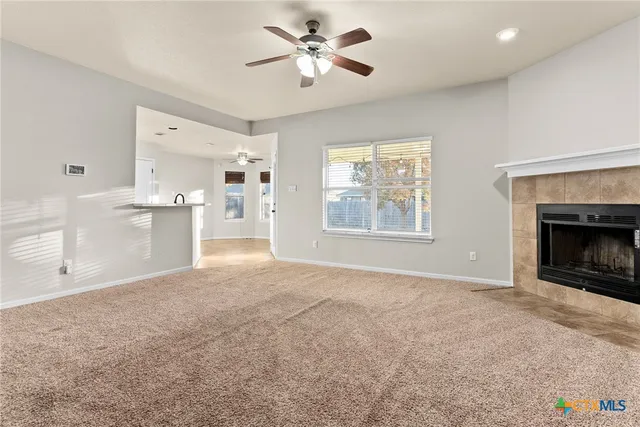 a view of an empty room with a window and a kitchen