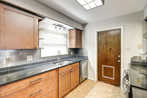 a kitchen with granite countertop a sink and a refrigerator