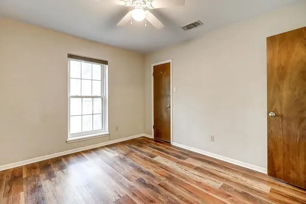 an empty room with wooden floor cabinet and windows