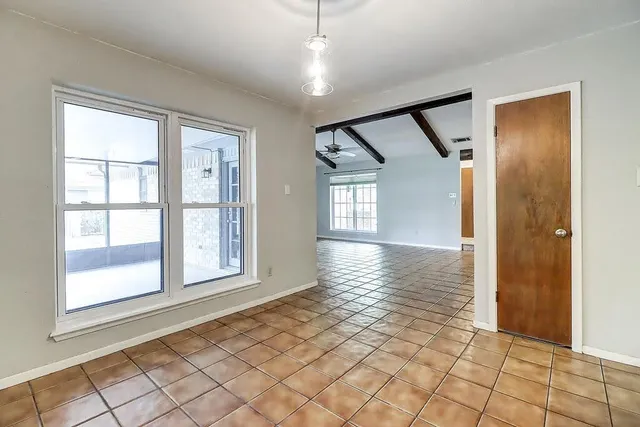 an empty room with wooden floor mirror and windows