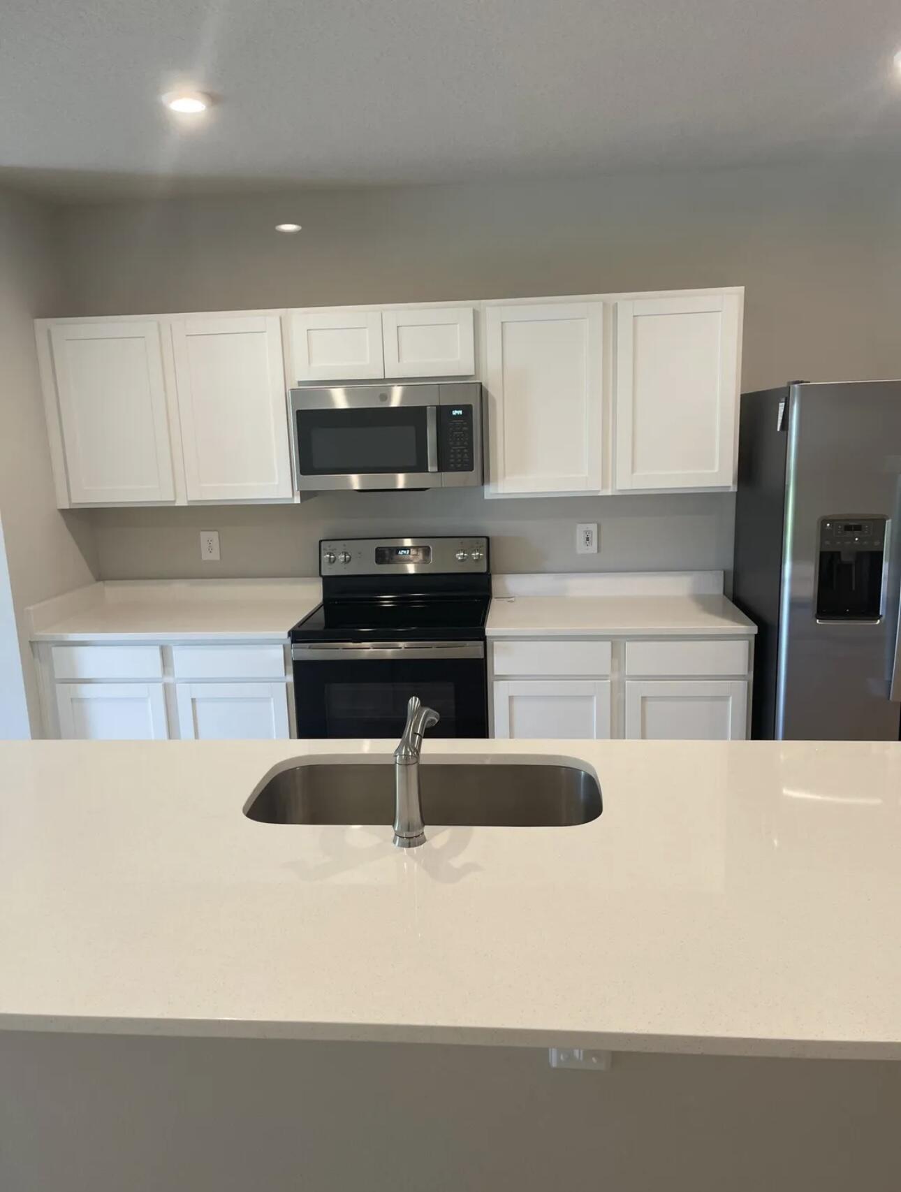a kitchen with a sink a stove and white cabinets