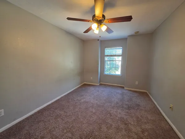 an empty room with windows and chandelier fan
