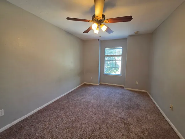 an empty room with windows and chandelier fan