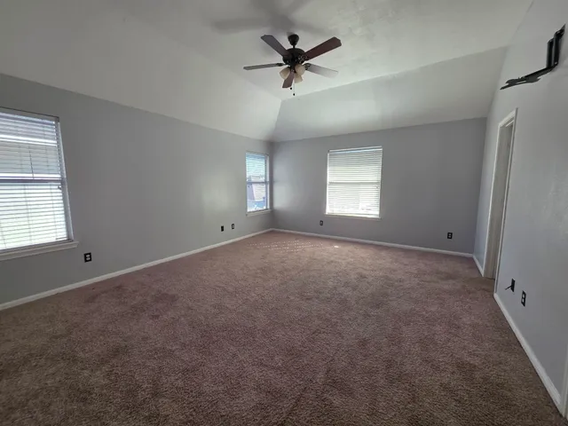 an empty room with windows and ceiling fan