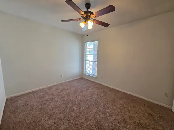 an empty room with a window and a fan