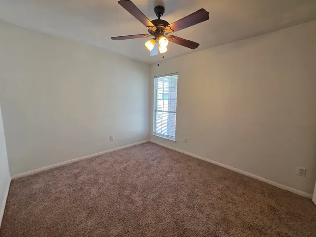 an empty room with a window and a fan