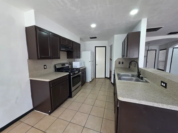 a large kitchen with stainless steel appliances wooden cabinets a stove and a sink