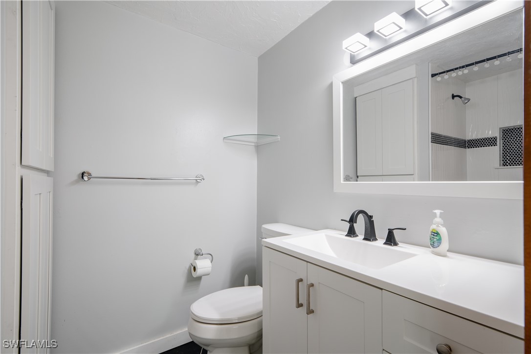 8025 Anhinga Road Fort Myers, FL 33967 - Photo 10 of 47 a bathroom with a toilet a sink a mirror and vanity