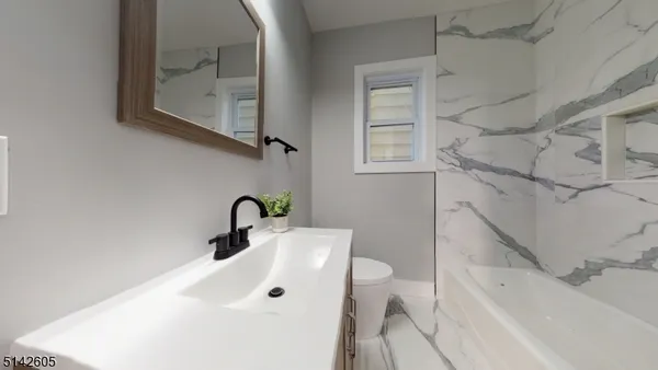a bathroom with a sink and mirror with bathtub