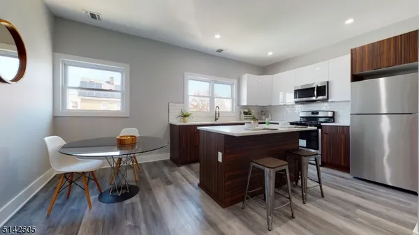 a kitchen with a dining table chairs and refrigerator