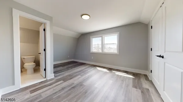 a view of a room with wooden floor and a bathroom
