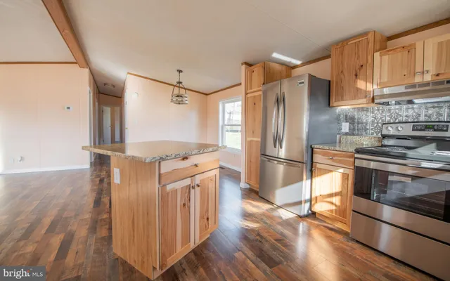 a kitchen with stainless steel appliances granite countertop a refrigerator a stove and a wooden floors