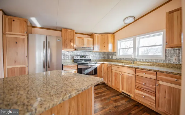 a kitchen with stainless steel appliances granite countertop a refrigerator sink and wooden cabinets